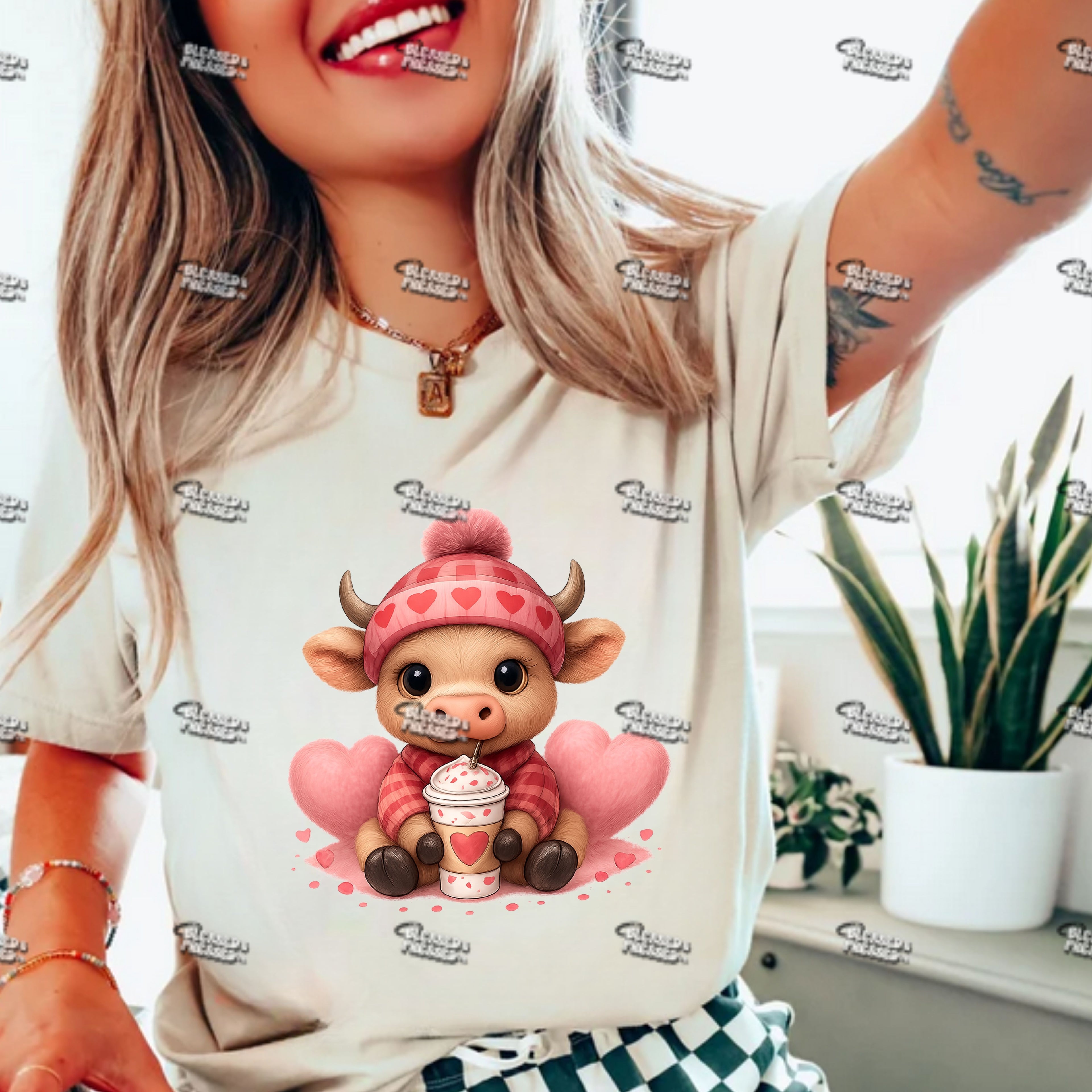 Person wearing a t-shirt with a cartoon bull design holding a cup and heart-shaped balloons.